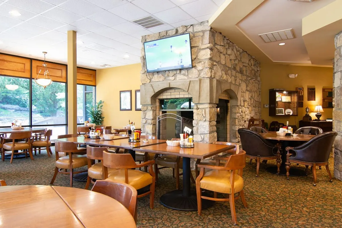 An inviting interior of the on-site restaurant, featuring a cozy stone fireplace, comfortable seating, large windows with views, and a welcoming atmosphere for meals or socializing. The space looks perfect for enjoying family dinners or relaxing after a day of activities.