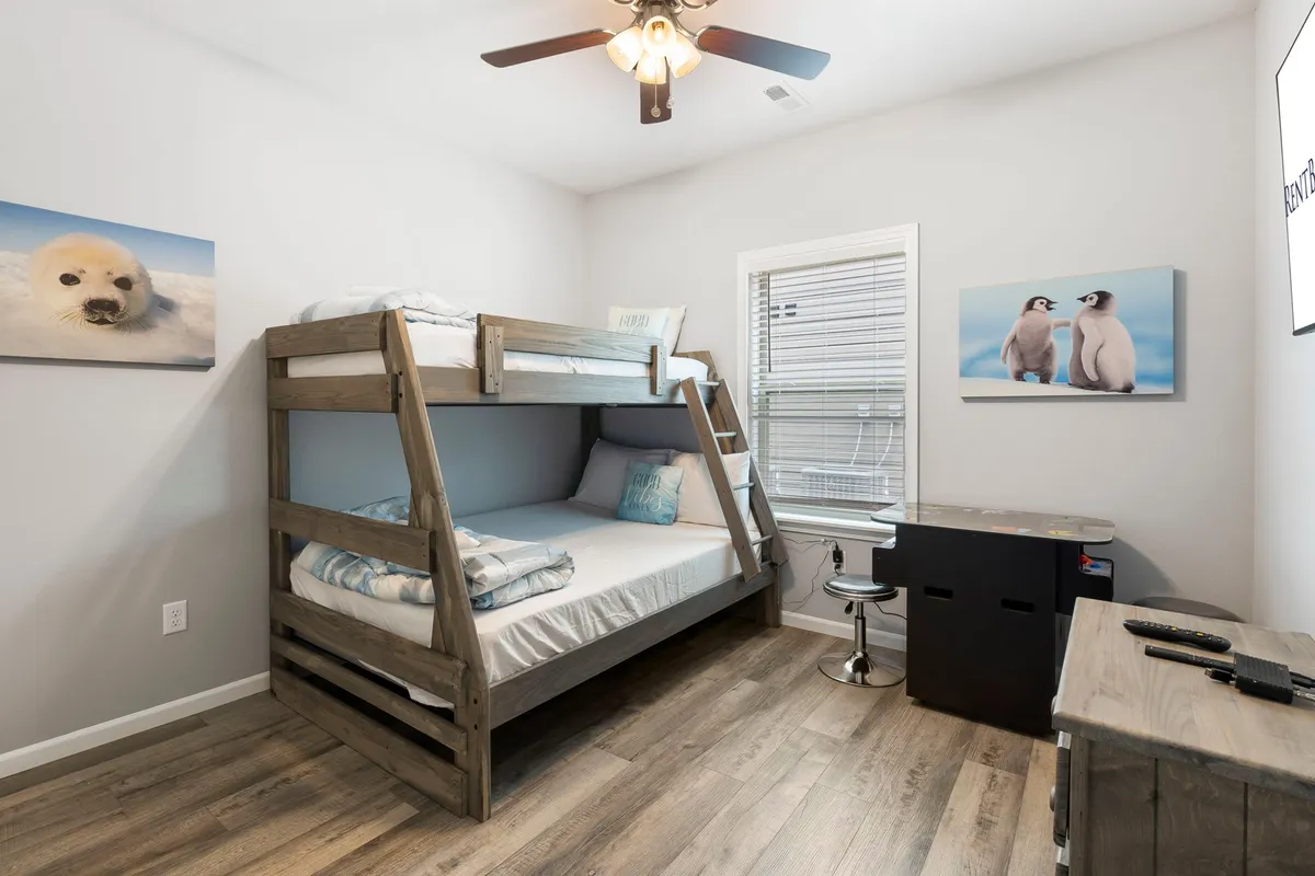A cheerful bunk room with a twin-over-full bunk bed, playful seal and penguin artwork, and a small desk with a stool. The decor and layout evoke a fun, kid-friendly environment ideal for imaginative play, bonding, and sleep.