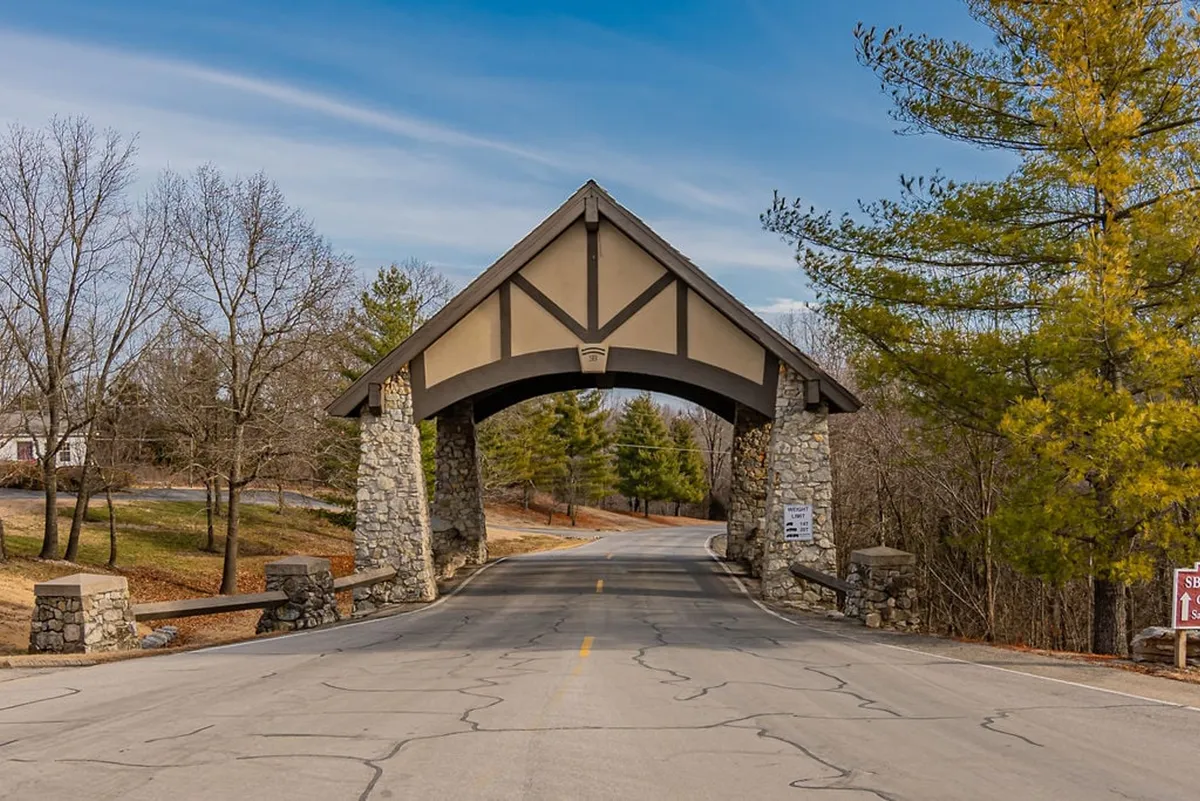 An inviting view of the resort’s arched stone entrance, with a roadway leading in, setting a welcoming tone for arrivals and hinting at the transition from the outside world into a private, relaxing retreat.