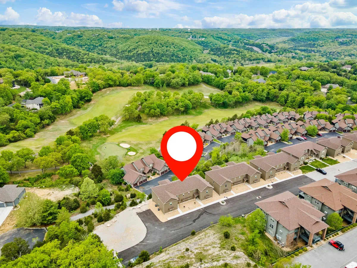 This exterior shot captures residential buildings nestled among greenery, with views of a golf course and inviting walking trails. The mood is tranquil, underscoring the resort's serene setting and access to scenic Ozark views.