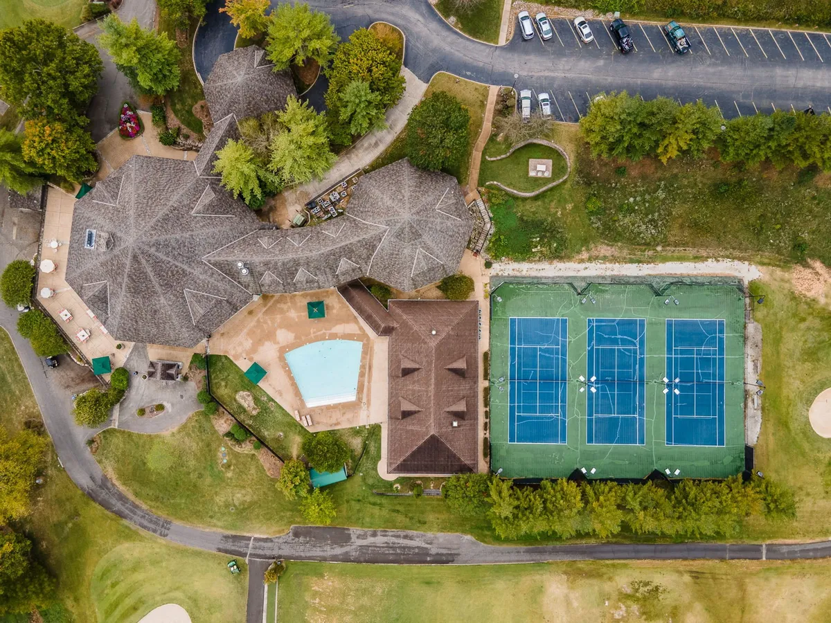 A vibrant exterior scene featuring the resort’s main building, a sparkling swimming pool, tennis courts, and lush landscaped gardens. The area radiates energy with spaces perfect for socializing, playing sports, and relaxing outdoors.